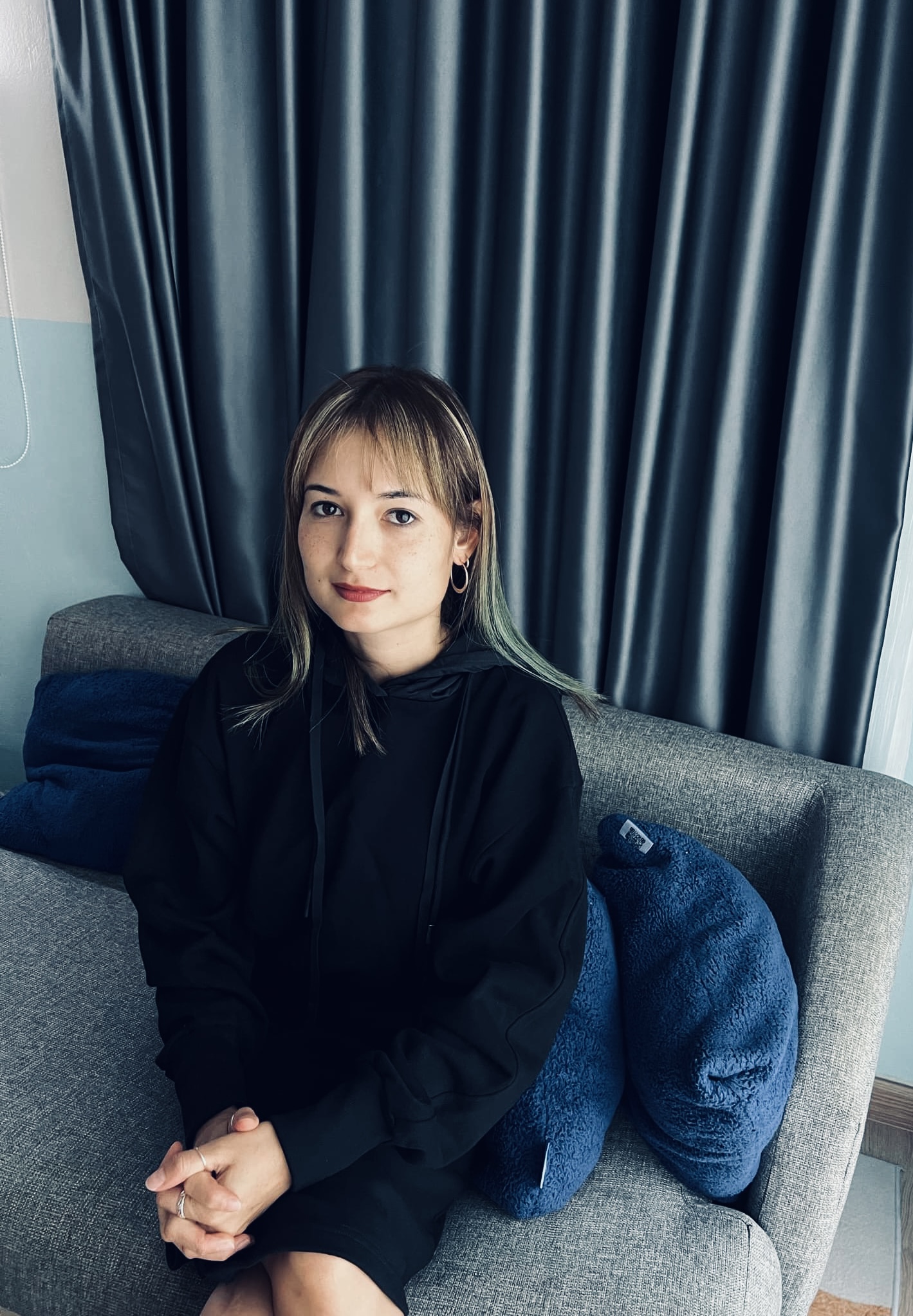 A photograph of Nina Culley sitting on a grey sofa