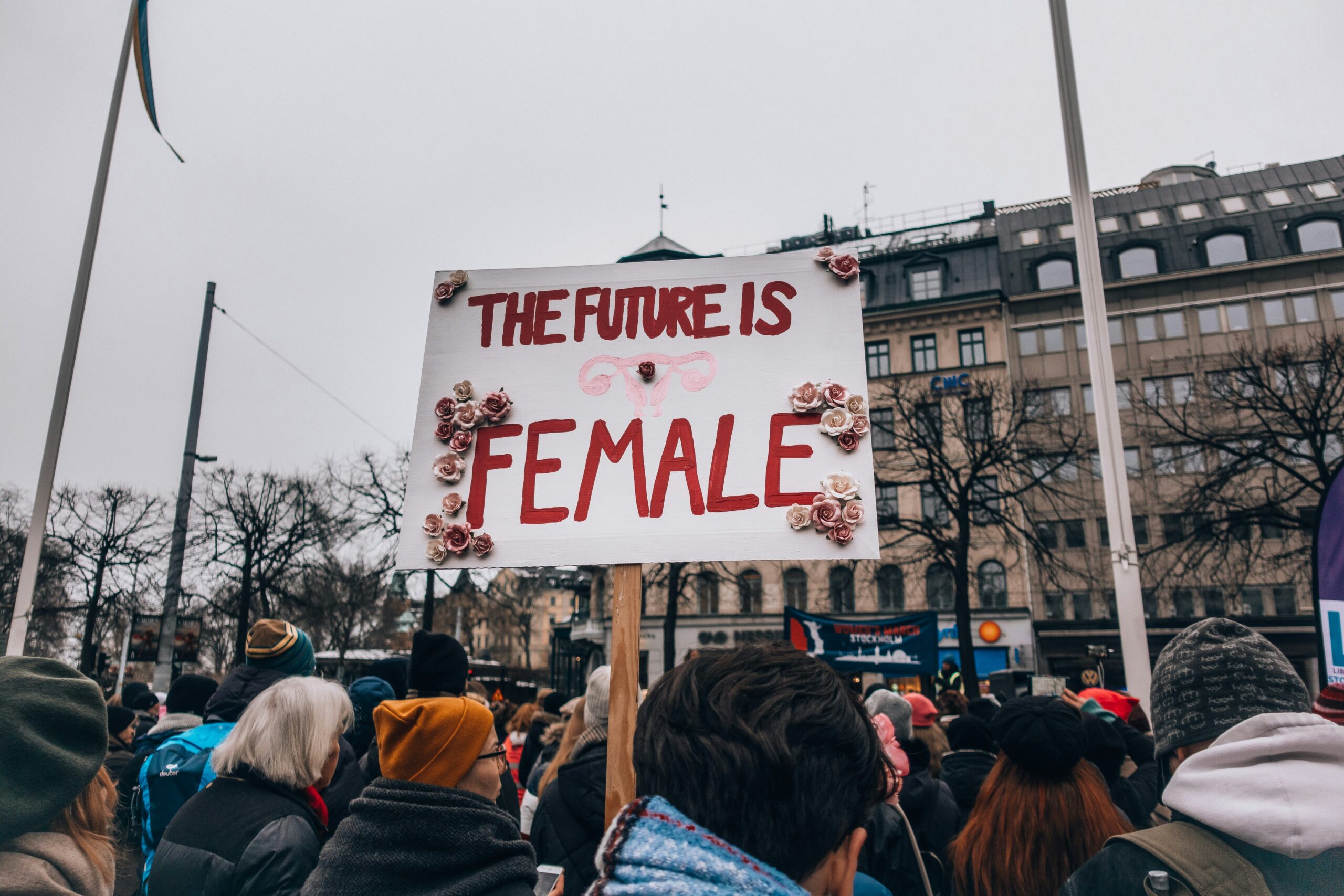 A protestor raises a placard into the air. It reads 'the future is female'.