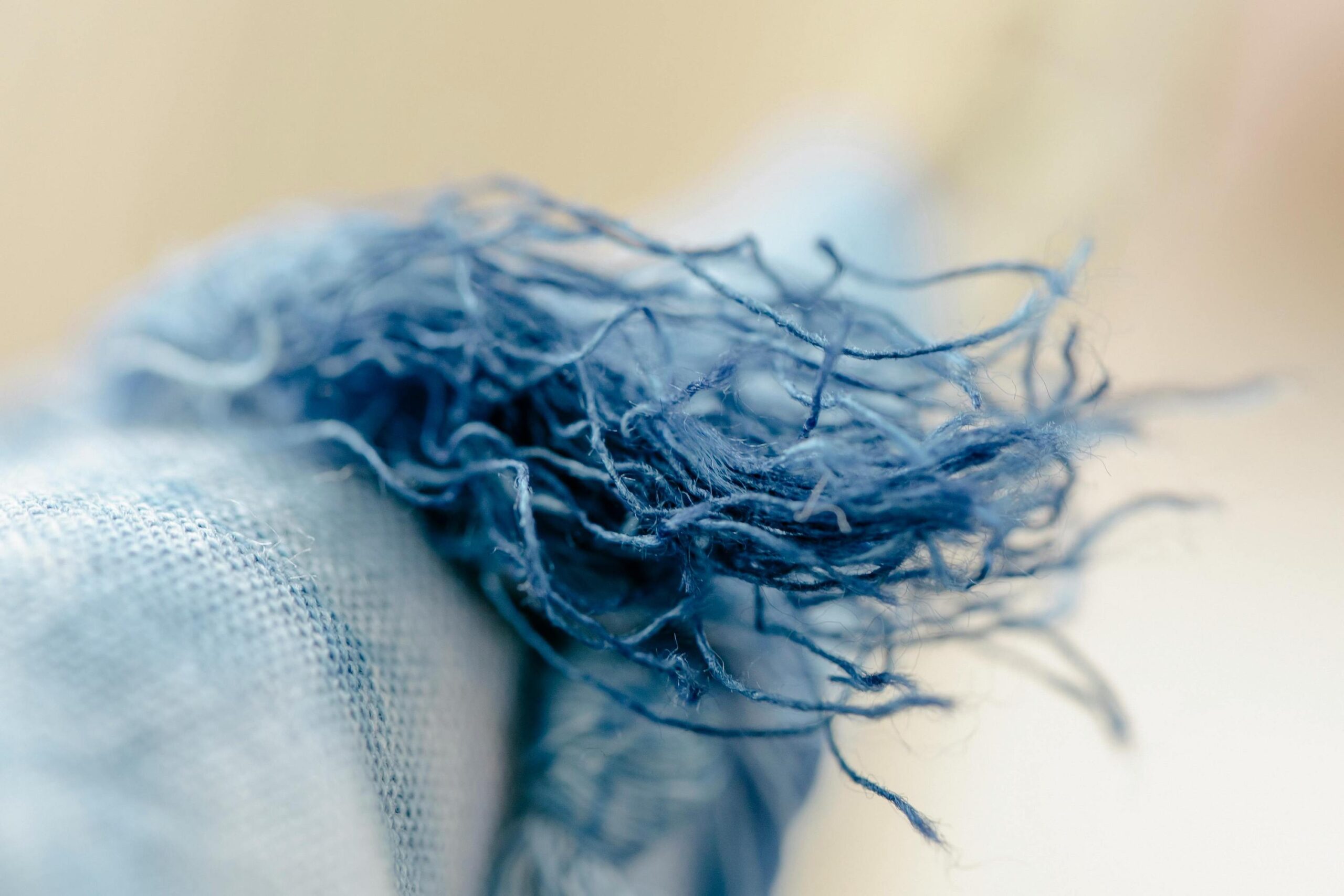A bolt of blue fabric frays against a neutral background