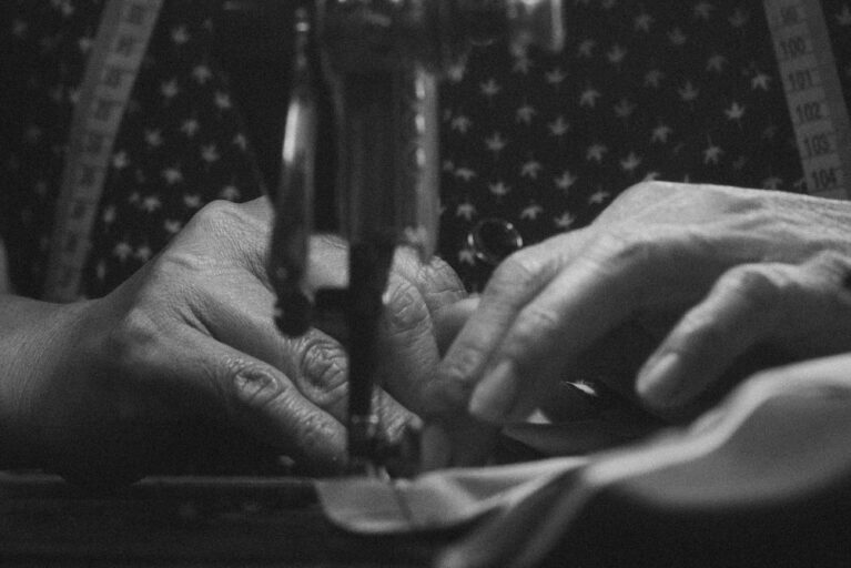 A woman's hands guide fabric through a sewing machine