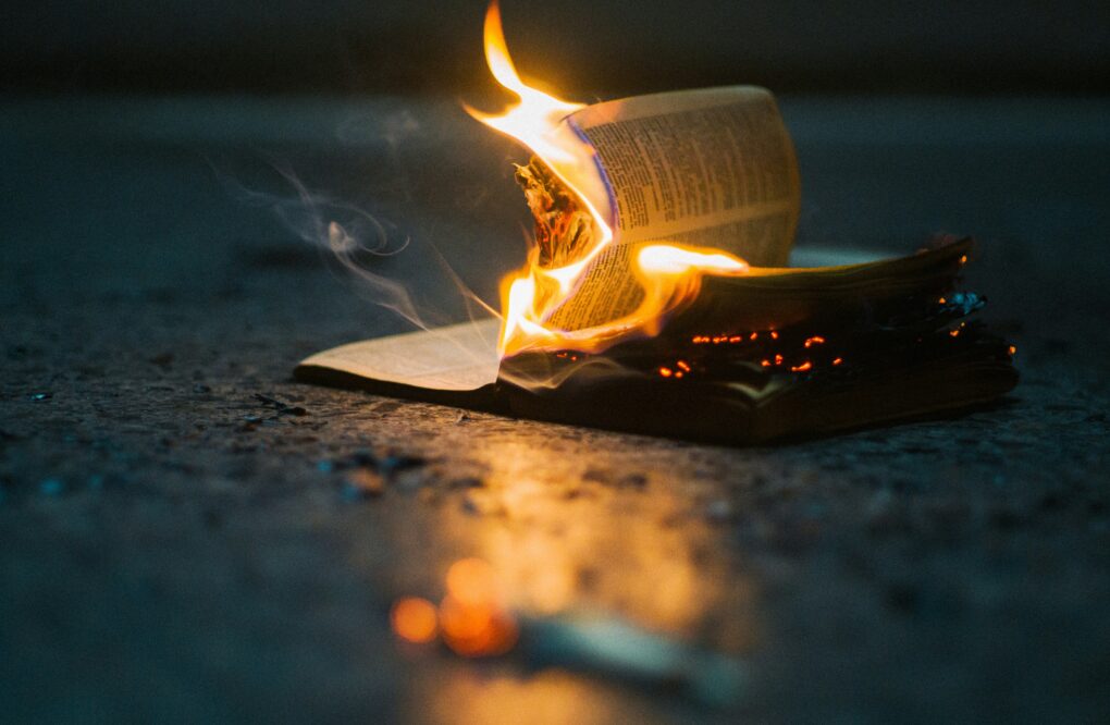 A single book upon concrete is consumed by flames.