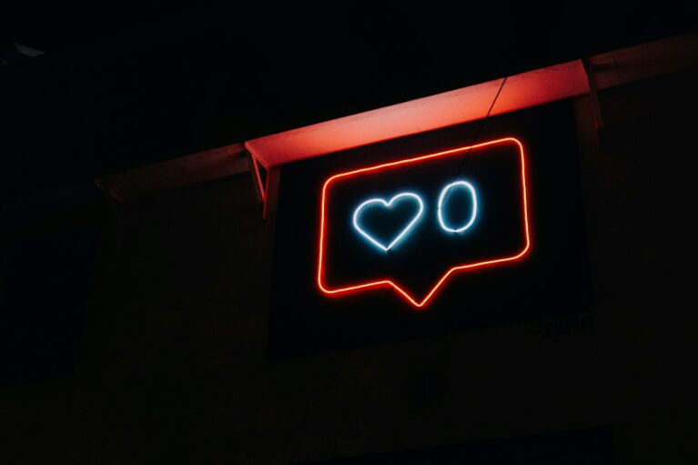 A neon number zero and love heart sit inside a red neon speech bubble