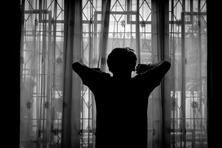A silhouette of a person staring out a window.