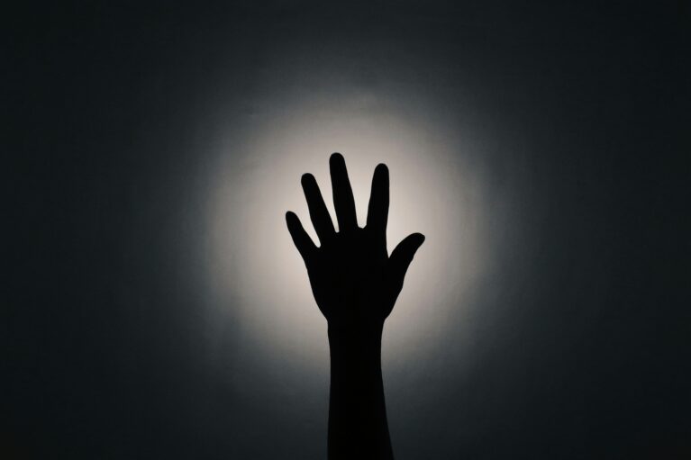 A silhouette of a hands reaching upwards