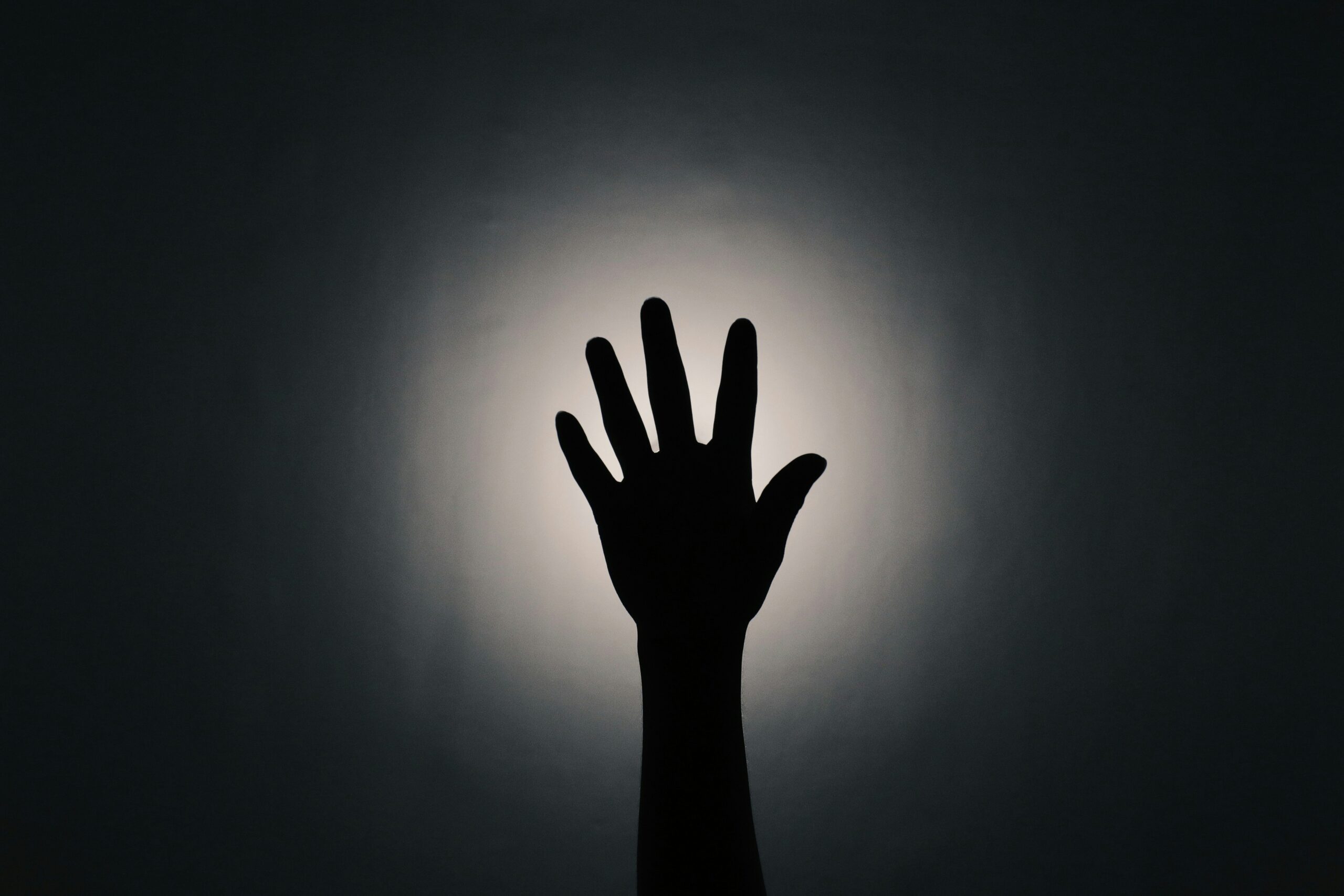 A silhouette of a hands reaching upwards
