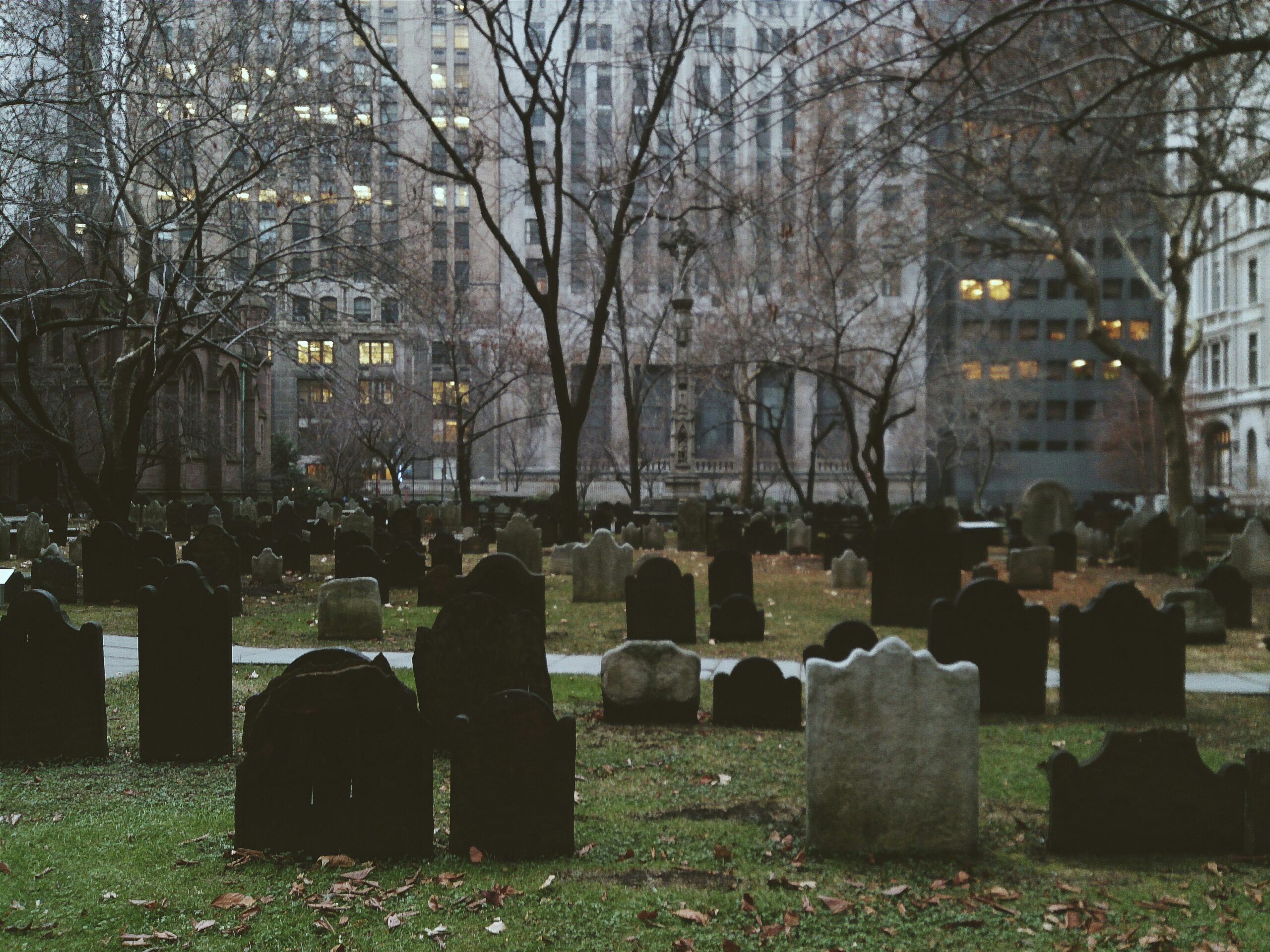 An image of a graveyard with large skyscrapers in the background