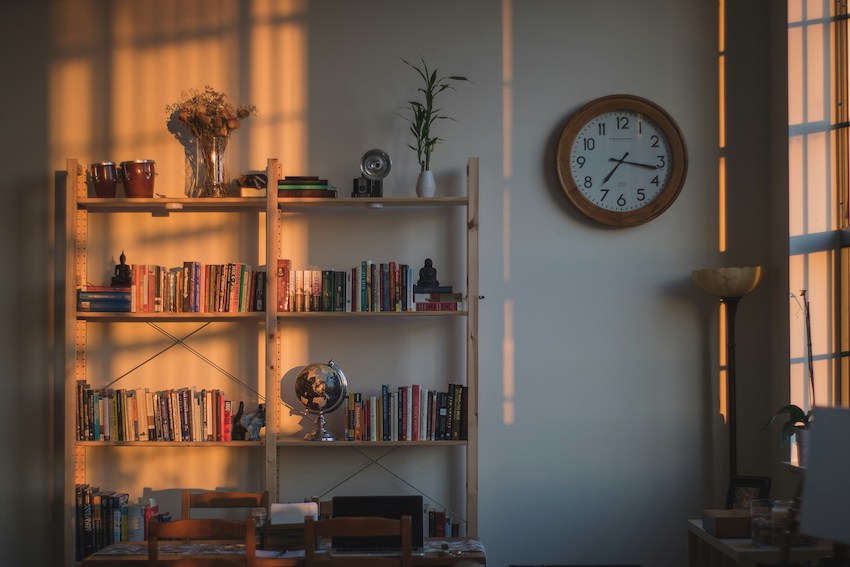 A bookshelf adorned with trinkets, such as a vase of flowers, a globe and several books