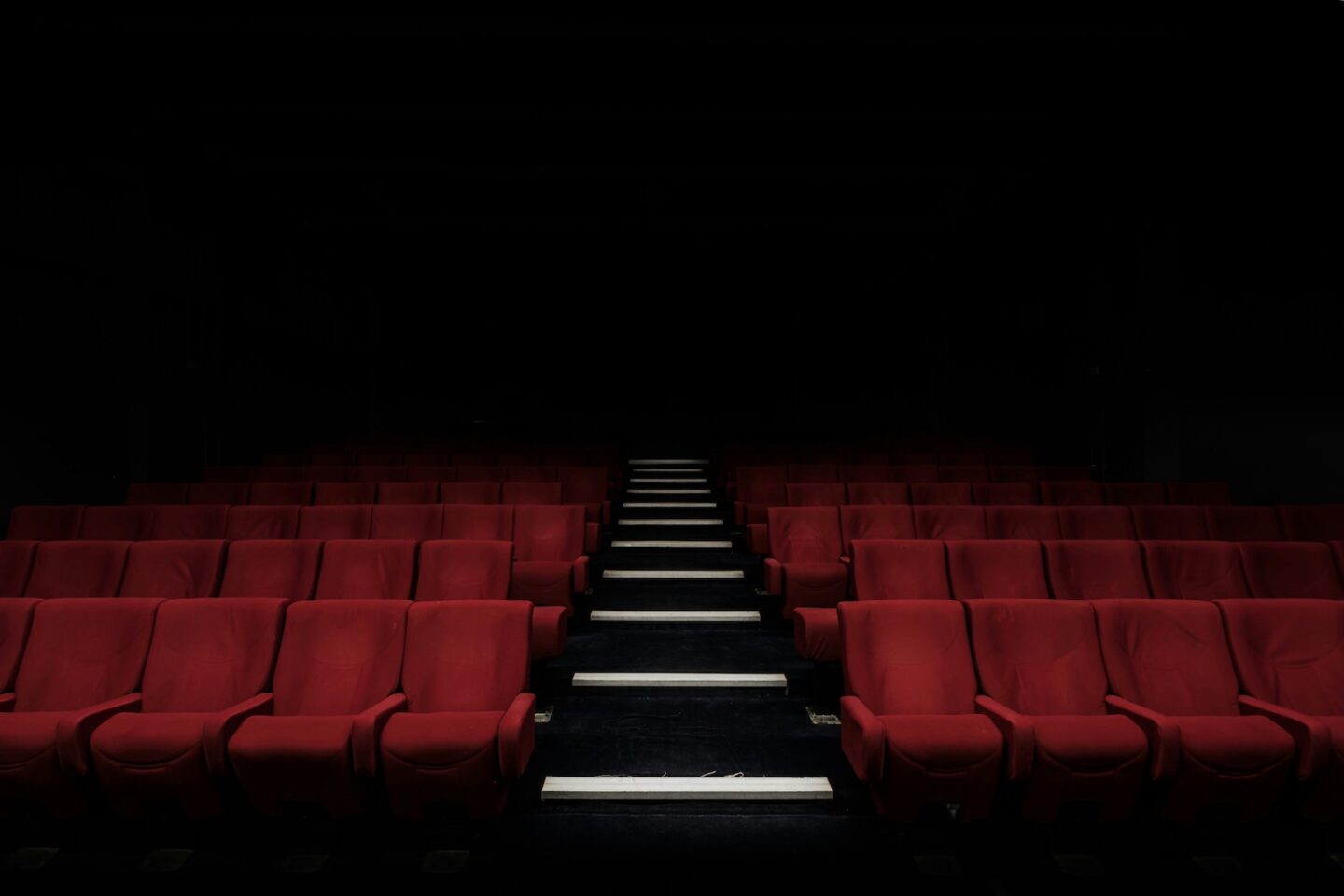 A picture of a vacant theatre with red velvet chairs