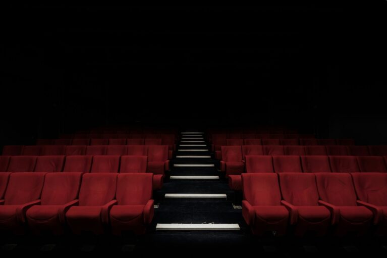 A picture of a vacant theatre with red velvet chairs